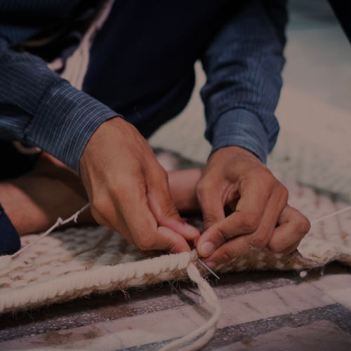 Hand finishing the edge of a woven rug