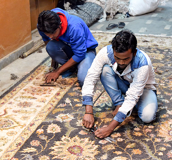 Artisans carefully finishing a handmade rug